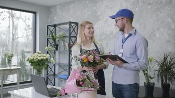 Flower delivery, portrait of young employees of modern flower boutique preparing list of delivery orders for beautiful bouquets of flowers, online service — 비디오