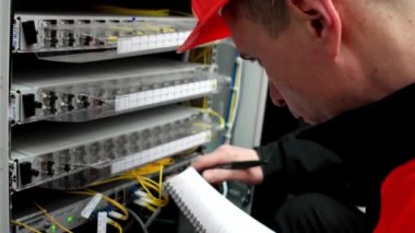 Telekomünikasyon ekipmanları, işçi adam sunucuya hizmet eder ve deftere yakın plan notlar yazar