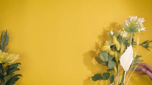 Floristería pone flores sobre fondo amarillo en movimiento rápido, hermosa composición con un lugar para su texto — Vídeo de stock