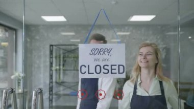 young male and female entrepreneurs small business owners change name from CLOSED to OPEN, smile look at camera and point fingers at it, successful startup