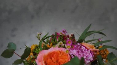 closeup of beautiful fresh flowers gathered in creative modern bouquet by young professional florist revolve dark background for an inscription, floristry