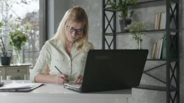 online service, a successful female entrepreneur works at computer in an office with fresh flowers checks an online order for flower delivery, small business