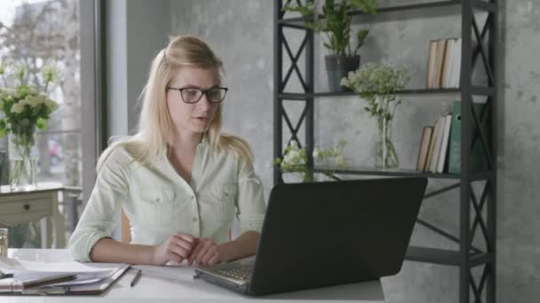 Успешный бизнес, молодая предпринимательница использует современные технологии для видеосвязи, женщина общается с партнерами, используя онлайн коммуникации, цветочный интерьер — стоковое видео