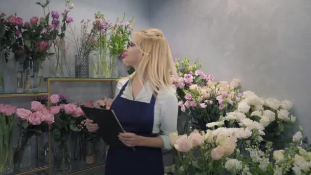 Loja de flores, retrato de mulher pequeno empresário proprietário de floristic boutique verifica flores em uma estufa sorrindo e olhando para a câmera, florista — Vídeo de Stock