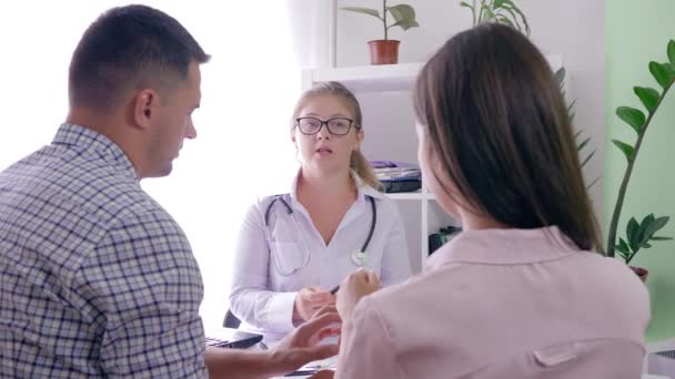 Cita con los médicos, médico mujer dice malas noticias sobre la salud de una mujer a la pareja casada en un consultorio médico en un hospital — Vídeos de Stock