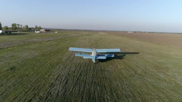 Blue aircraft takes off over field against sky and horizon line in spring — Stock Video