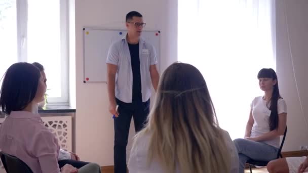 Psicólogo masculino realiza treinamento para jovens durante reunião psicológica no fundo do conselho com palavra - motivações — Vídeo de Stock