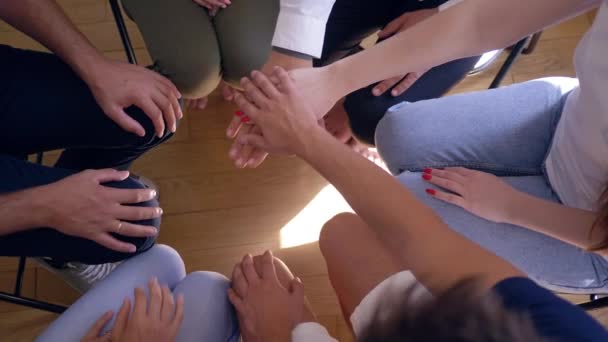 Esprit d'équipe, les jeunes faisant pile de mains se déplaçant vers le haut et vers le bas assis en cercle sur la thérapie de groupe — Video