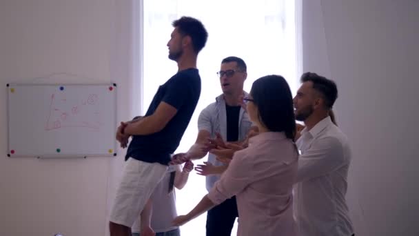 Trust fall, man falls on back and colleagues catch and applaud him on group therapy — Wideo stockowe