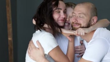 boy hugs his young parents close up, family have fun together in studio on photo shoot