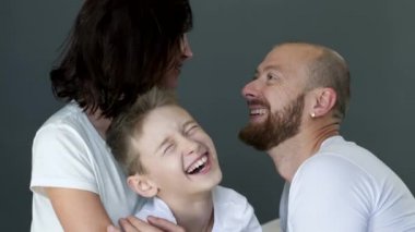 happy family in identical white T-shirts hugs each other close up in studio on photo shoot
