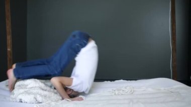 Mutlu kaygısız çocuk ağır çekimde yatakta takla atıyor.