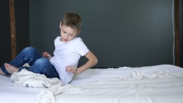 Happy childhood, boy flips on bed in slow motion at bedroom — 图库视频影像