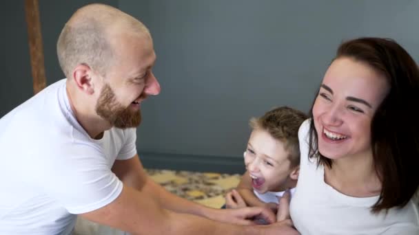 Padres alegres con hijo divertirse en la cama en casa en el dormitorio, momentos felices — Vídeos de Stock