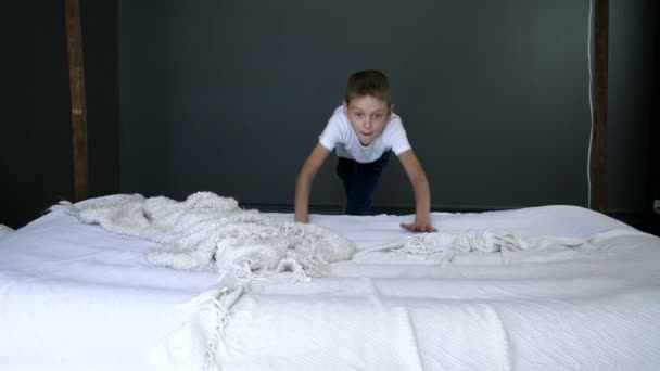 Unterhaltung, fröhlicher Junge rennt und springt im Schlafzimmer in Zeitlupe aufs Bett — Stockvideo