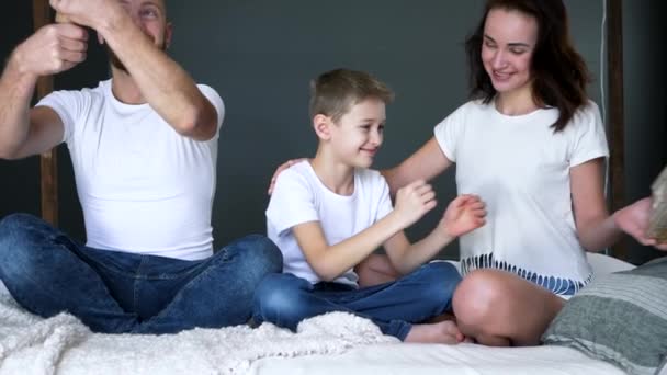 Heureux garçon tient présent dans les mains près de maman tandis que le jeune père fait sauter cracker avec des confettis — Video