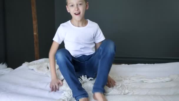 Home entertainment, jongen springt op bed in slow motion en veel plezier op de kamer — Stockvideo