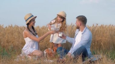 Aile çayırı pikniği, küçük kız anne babasının bardaklarına süt döker ve süt içerek iletişim kurarlar.