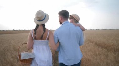 Aile ilişkisi, genç kırsal aile buğday tarlasında bir sepet taze ekmek ve çörekle yürüyüp sohbet ediyor.