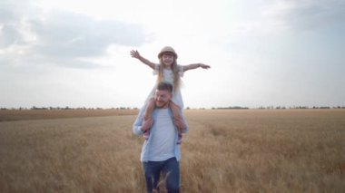 Mutlu aile anları, genç baba omuzlarında küçük bir kızla koşar. Çığlık atar, sevinir, güler ve ellerini kaldırır hasat mevsiminde olgunlaşmış buğday tarlaları arasında.