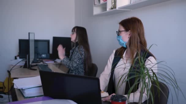 Хвороба в офісі, жінка в окулярах для зору маскований працівник використовує антисептичні препарати поблизу хворого колеги при роботі на комп'ютері для захисту коронавірусу, концепція пандемії вірусу — стокове відео