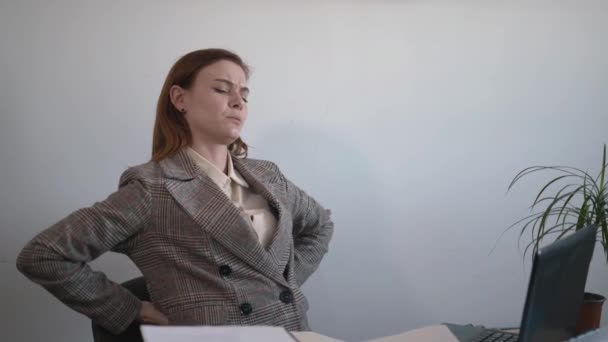 Gezondheid, zakenvrouw lijdt aan rugpijn als gevolg van onjuiste houding tijdens het zitten achter de computer tijdens het werk in het kantoor, pijn in de wervelkolom — Stockvideo