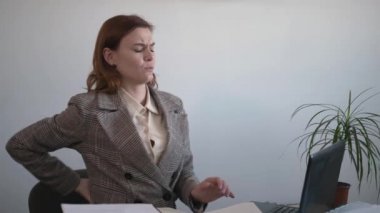 Yorgun ve yorgun bir kadın sırt ağrısını hisseder. Omurga kasları sırt ağrısından muzdariptir. Ofisteki bilgisayarda yanlış poz verdikten sonra.