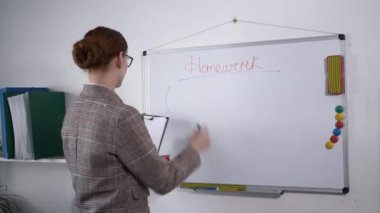 Vizyon gözlüklü genç bayan matematik öğretmeni, çocuklara eğitim verirken, sınıfta işaretli manyetik karatahtaya bir denklem yazıyor.