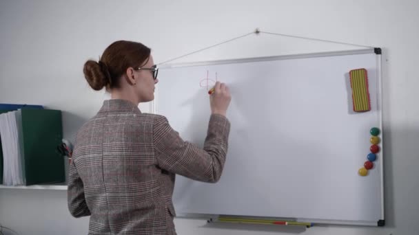 Jonge vrouw zakenvrouw of leraar schrijft huiswerk voor studenten op whiteboard met uitwisbare marker — Stockvideo