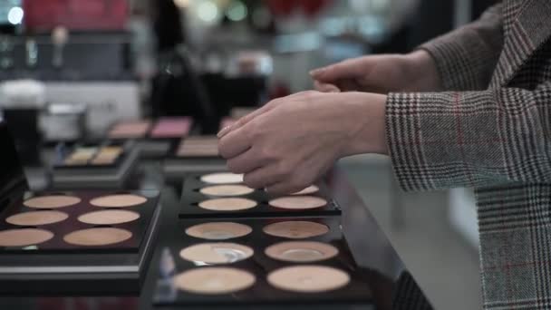žena nakupující testuje kosmetiku obličeje v profesionálním obchodě, detailní záběr ženských rukou vybírá make-up pudr pozadí kosmetiky