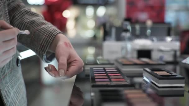 Maquillaje, chica de compras con cepillo en las manos está probando cosméticos para el maquillaje de ojos en la tienda — Vídeos de Stock