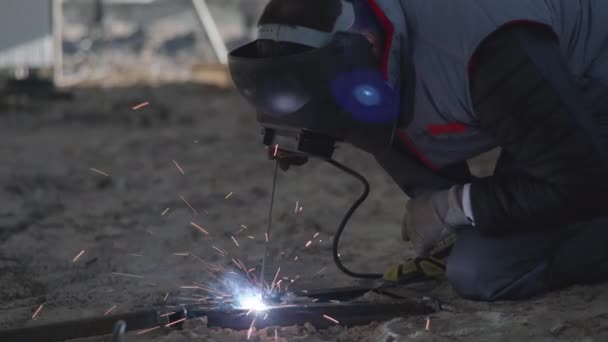 Industri, manlig svetsare i skyddshjälm, kläder och handskar utför metallarbete med svetsmaskin under byggandet av hangar mitt i gnistor — Stockvideo