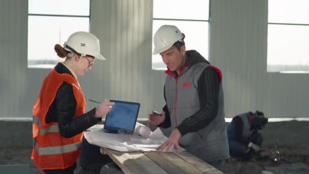 Construction manager female architect and consultant welder in protective helmets discuss new hangar project — Stock Video