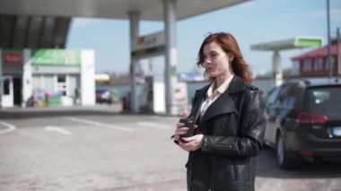 Servis, tatmin olmuş kadın müşteri benzin ve yakıt fiyatlarıyla dolu bir arabada kahve içerken...