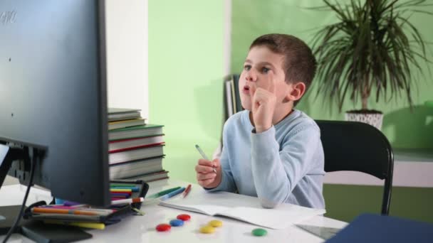 Home schooling, male child elementary school student writes assignment in notebook during online quarantined distance learning lessons due to pandemic, self-isolation — Stock Video