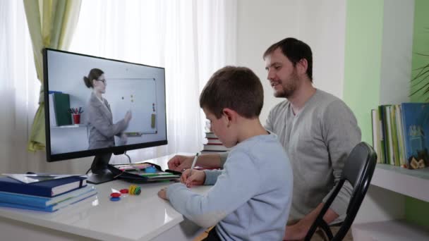 Estudiar en casa, un niño con el padre estudiando en las escuelas en línea, viendo la transmisión de vídeo de la lección en la pantalla del ordenador durante la cuarentena y la pandemia, coronavirus — Vídeos de Stock