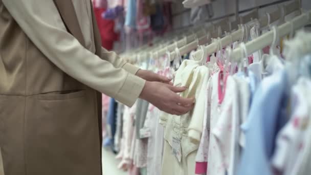 Mutterschaft, glückliche junge Frau, Käufer wählt Kleidung für Kinder, Mutter im Geschäft probiert qualitativ hochwertige Kinderkleidung, Nahaufnahme — Stockvideo
