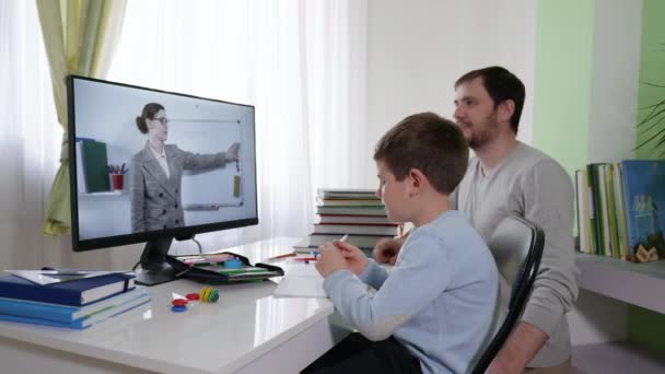 Niños aprendiendo en línea, padre ayuda a su hijo a aprender lecciones utiliza la tecnología moderna para la educación a distancia sentado en casa en la computadora — Vídeo de stock