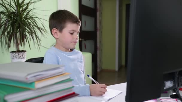Menino inteligente em ensina currículo escolar on-line enquanto sentado em casa no computador, criança levanta a mão e responde perguntas para o professor em uma lição on-line — Vídeo de Stock