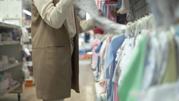 Ropa recién nacido, mujer cliente en el departamento de ropa de los niños elige cosas para su hijo en los grandes almacenes, primer plano — Vídeos de Stock
