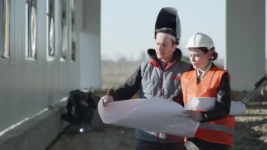 Miğferdeki kadın mimar mühendisi profesyonel ekipman kaynakçısı ve koruyucu kask inşaatı veya kaynak ve kıvılcımların bazı bölümleri ile görüşüyor.