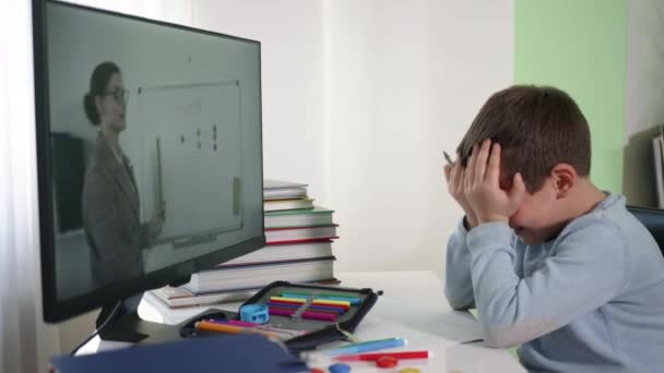 Niño estudiante de primaria sufre de la educación en casa en línea no entiende las explicaciones del maestro — Vídeos de Stock