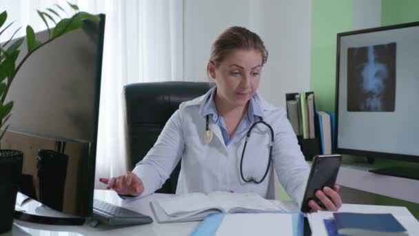 Σε απευθείας σύνδεση γιατρός, ένας ιατρικός επαγγελματίας συμβουλεύει τον ασθενή χρησιμοποιώντας το κινητό τηλέφωνο και δίνει συστάσεις για την ανάκαμψη από το γραφείο — Αρχείο Βίντεο