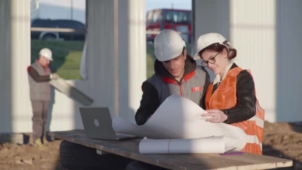 Architect and engineer viewing a building project of an indoor construction site on site of background working person — Stock Video