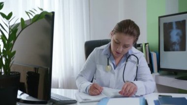Modern tıp, kadın doktor modern uygulamalarla hastalarla konuşuyor ve hastalık belirtilerini tıp kitabına yazıyor.
