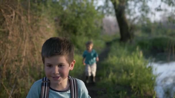 Bambini maschi che si rincorrono su strada lungo il fiume — Video Stock