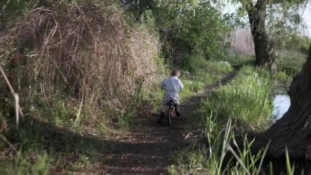 Gesunde Lebensweise, ein aktiver kleiner Junge hat Spaß am Wochenende Radfahren entlang des Weges — Stockvideo