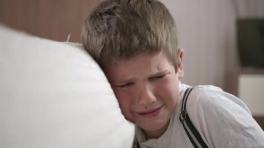 Çocukluk sorunları, ailedeki yanlış anlaşılmalar ya da depresyon yüzünden ağlayan üzgün erkek çocuk kanepenin yanındaki odada oturuyor.