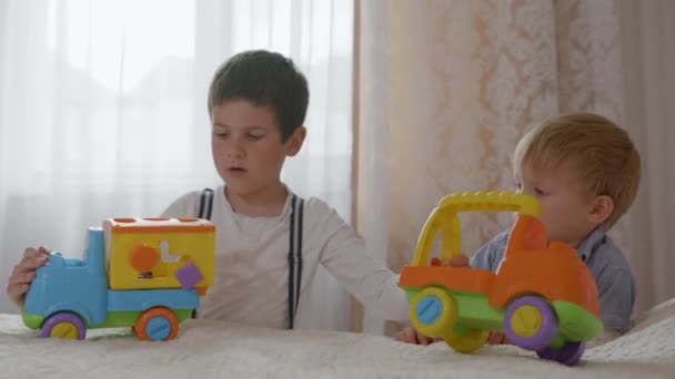 Relacionamento de crianças, meninos bonitos amorosos parentes jogar junto com carros de brinquedo coloridos de plástico juntos — Vídeo de Stock