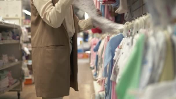Maternidad, cliente joven en el departamento de ropa para niños elige cosas para su hijo en la tienda minorista, primer plano — Vídeos de Stock